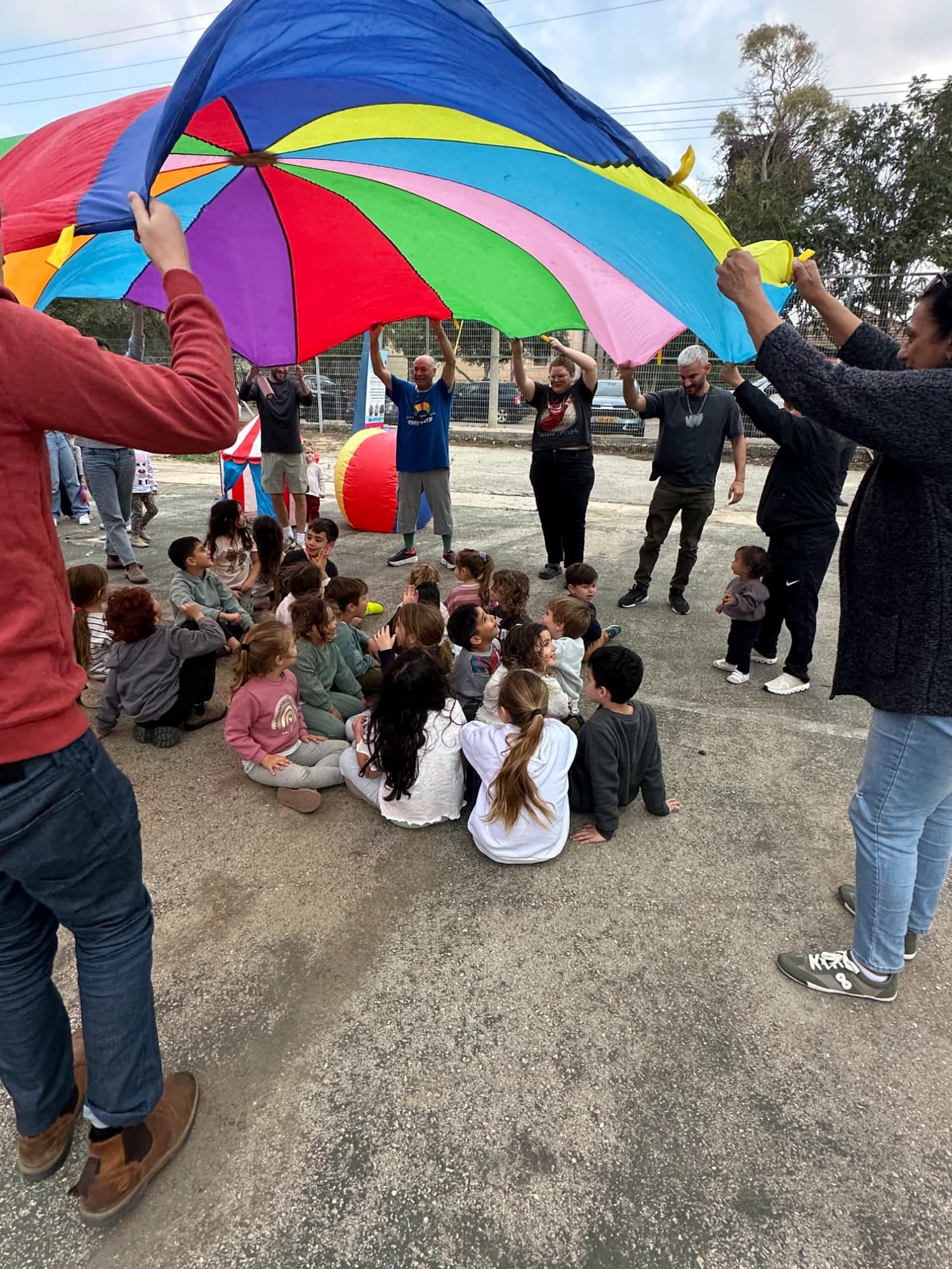 ילדים נהנים מהפעלה עם מצנח צבעוני ענק באירוע של נוני אירועים